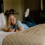 Relaxed woman lying on hotel bed in Eureka Springs, Arkansas, enjoying a vacation.