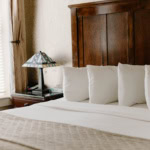 A cozy hotel bedroom with a wooden headboard and white bedding.