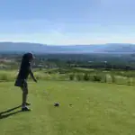 golfer on tee box overlooking city and lake views