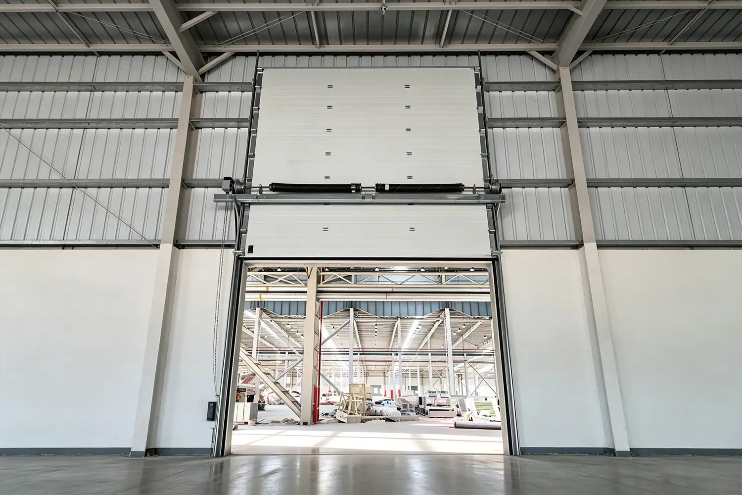Interior view of a high-performance industrial sectional door featuring European-standard hardware, torsion springs, and universal tracks installed in a modern manufacturing facility.