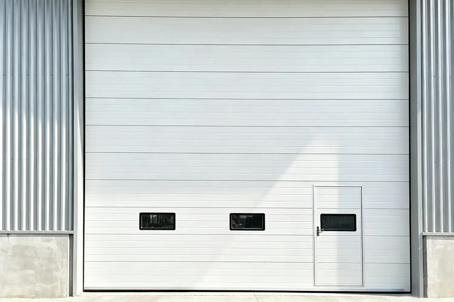 Heavy-Duty Industrial Sectional Overhead Door with Integrated Wicket Door and Vision Panels Installed in Cold Storage Facility