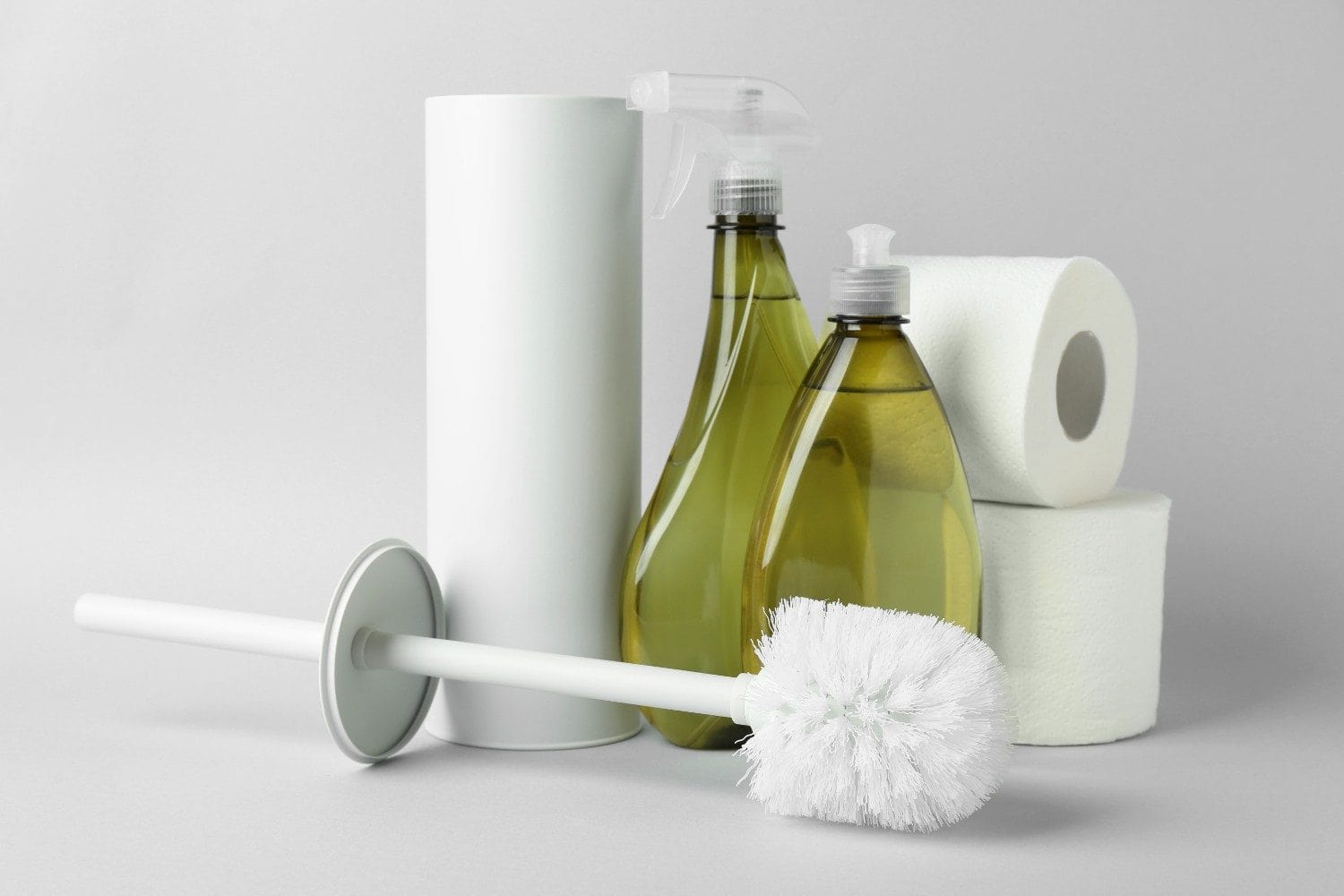 Flat-lay view of a toilet brush and drain cleaners on a neutral background.