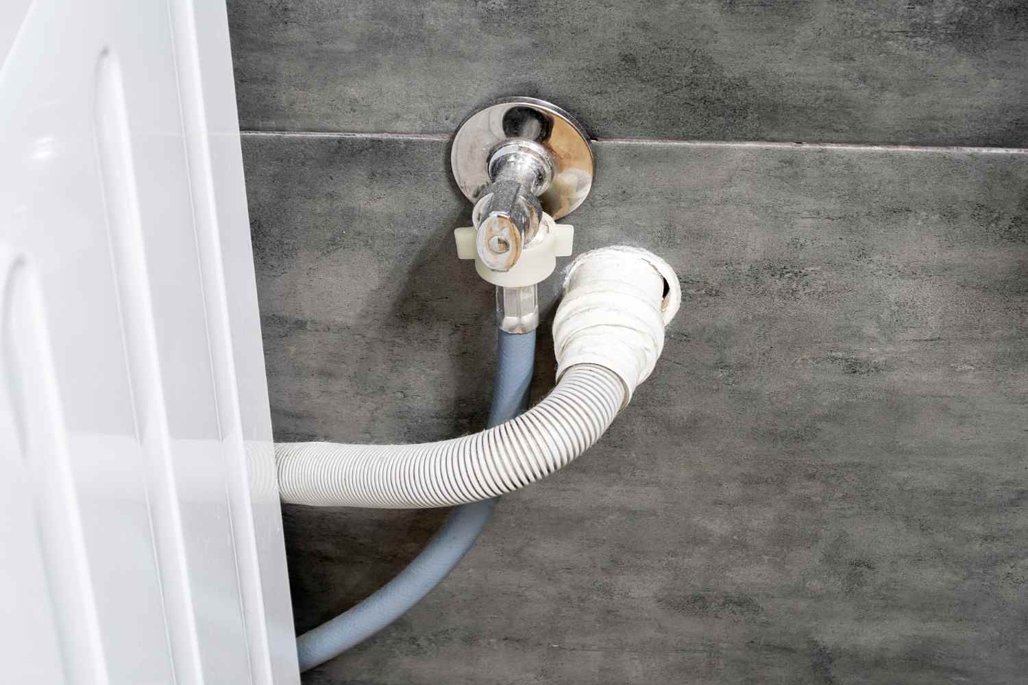 Washing machine drain hose connected to a standpipe behind a front-load washer.