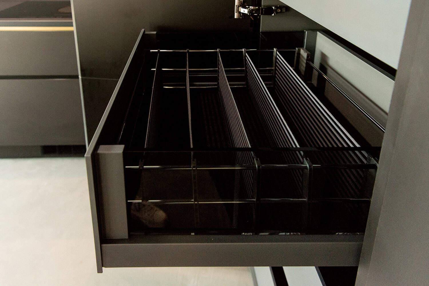 Pulled-out kitchen cabinet drawer featuring wire mesh divider inserts.
