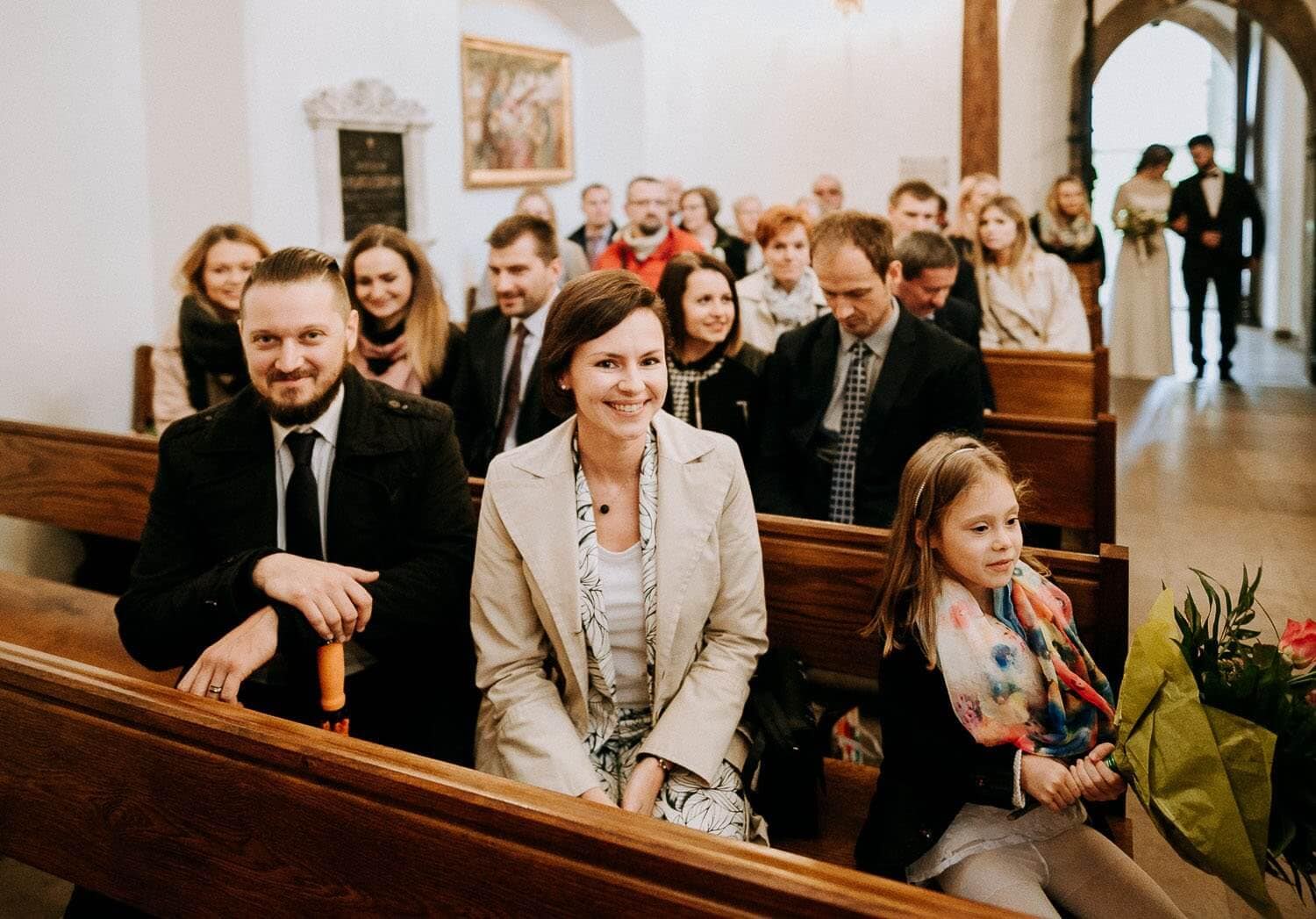 goscie weselni siedza w kosciele i czekaja na pare mloda