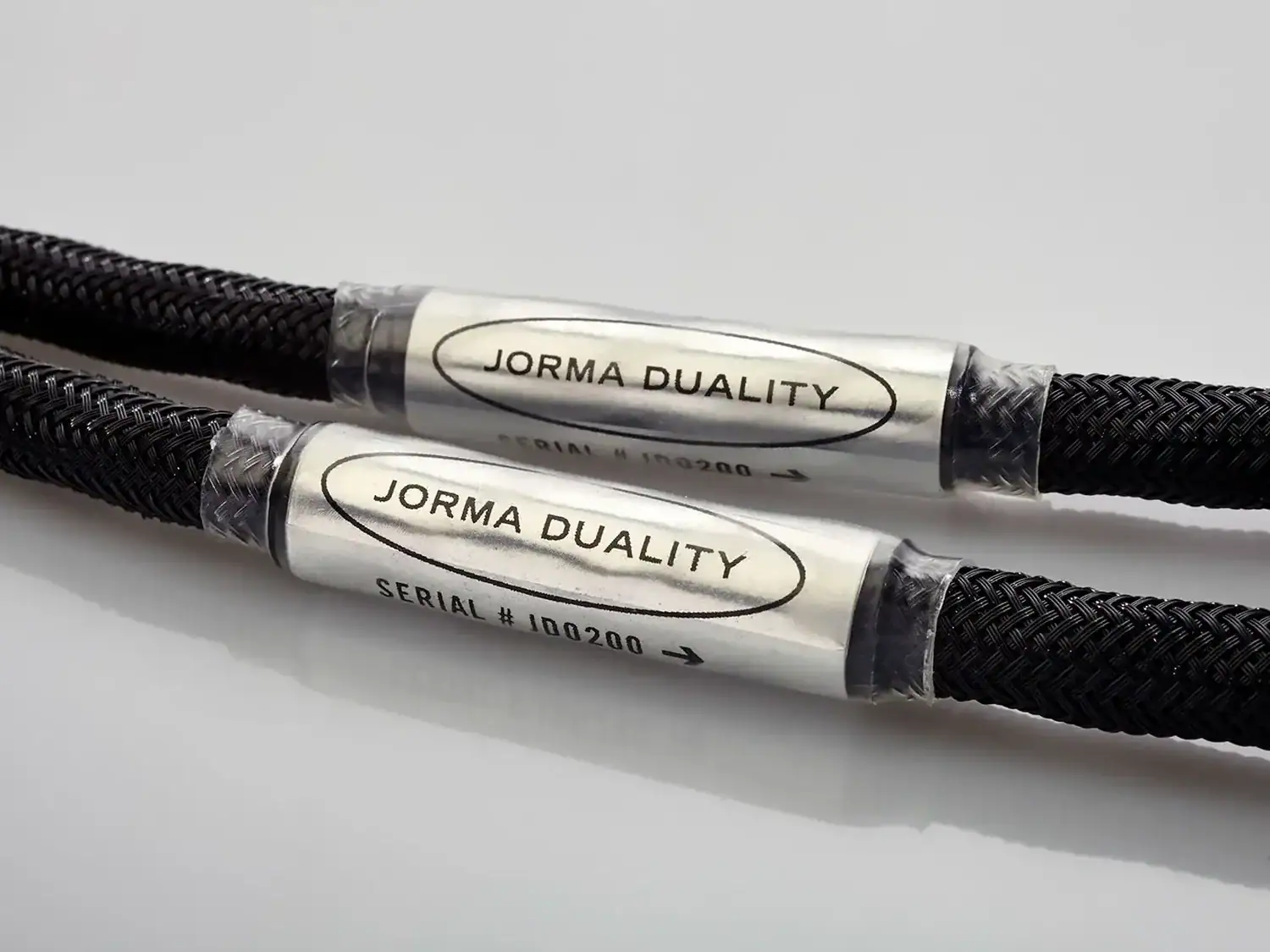 Paire de câbles haut-parleur Jorma Duality côte à côte avec les étiquettes de reconnaissance du modèle autour des gaines