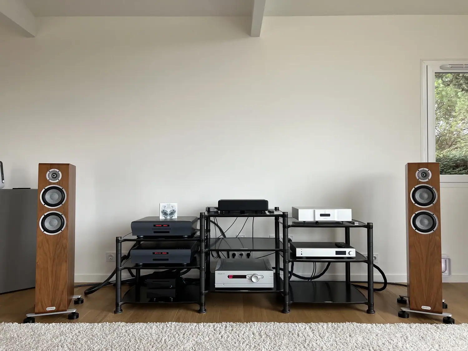 Marten Oscar Trio en situation de part et d'autre d'un rack Hi-fi avec des électroniques