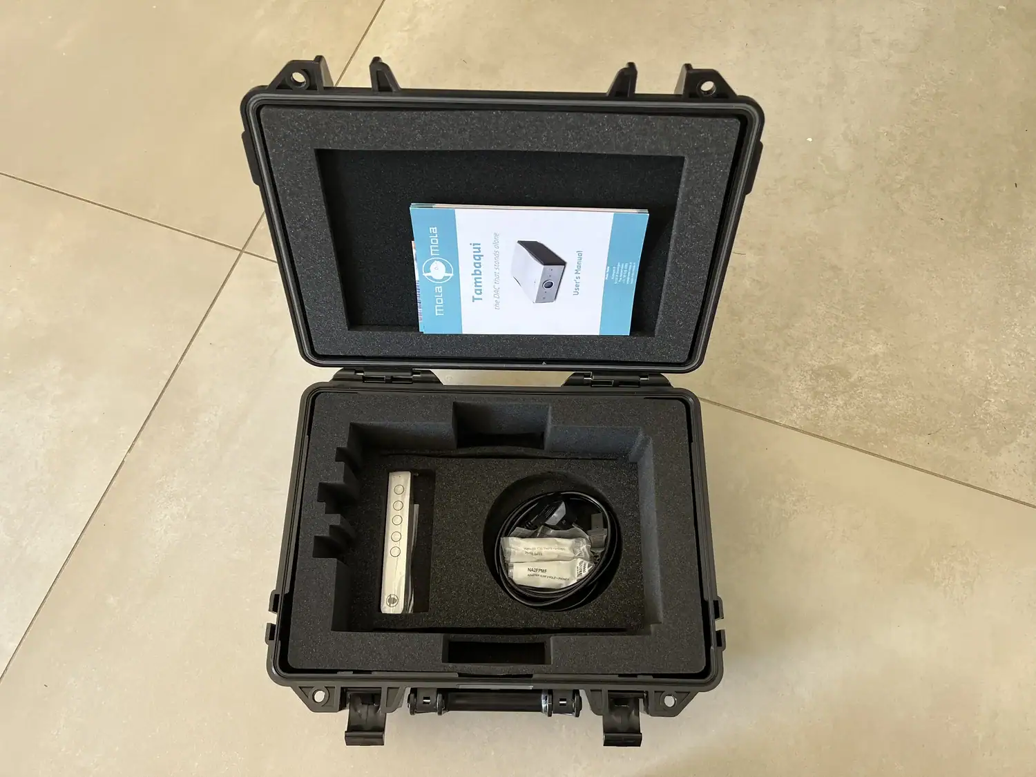 Flight-case du Mola-Mola Tambaqui ouvert avec la télécommande et les adaptateurs RCA vers XLR dans les compartiments situés au fond