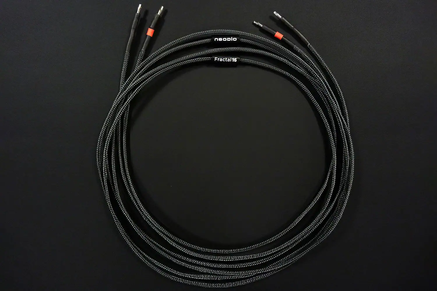 Paire de câbles haut-parleurs Neodio Fractal-L enroulés sur fond noir