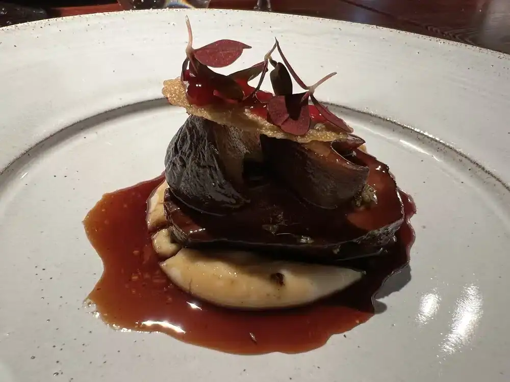 Plat de viande avec une sauce caramel et des fleurs rouges