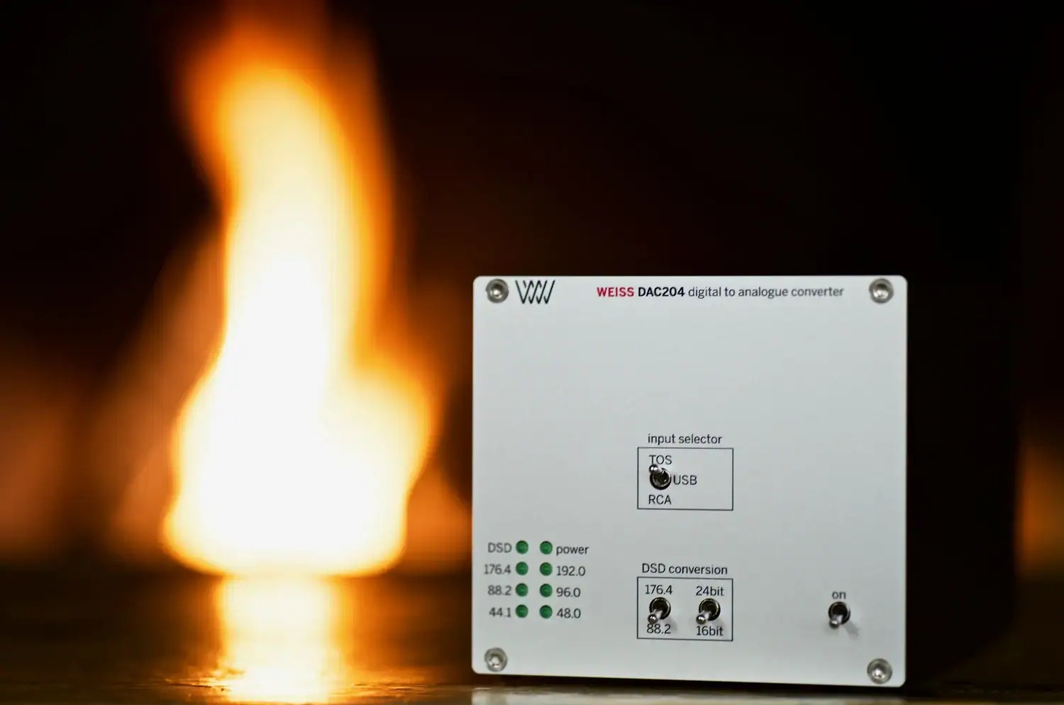 Weiss DAC204 vue de la façade avec un feu de cheminée flou en arrière plan