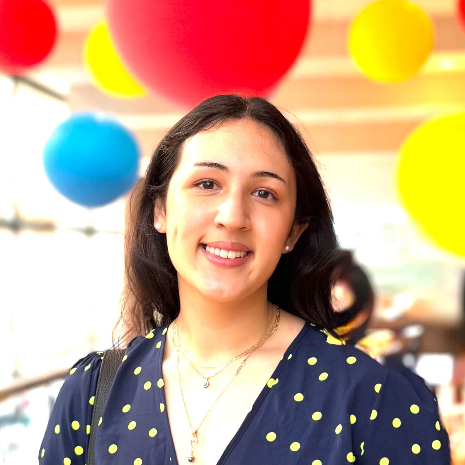 Woman smiling in front of colourful balloons