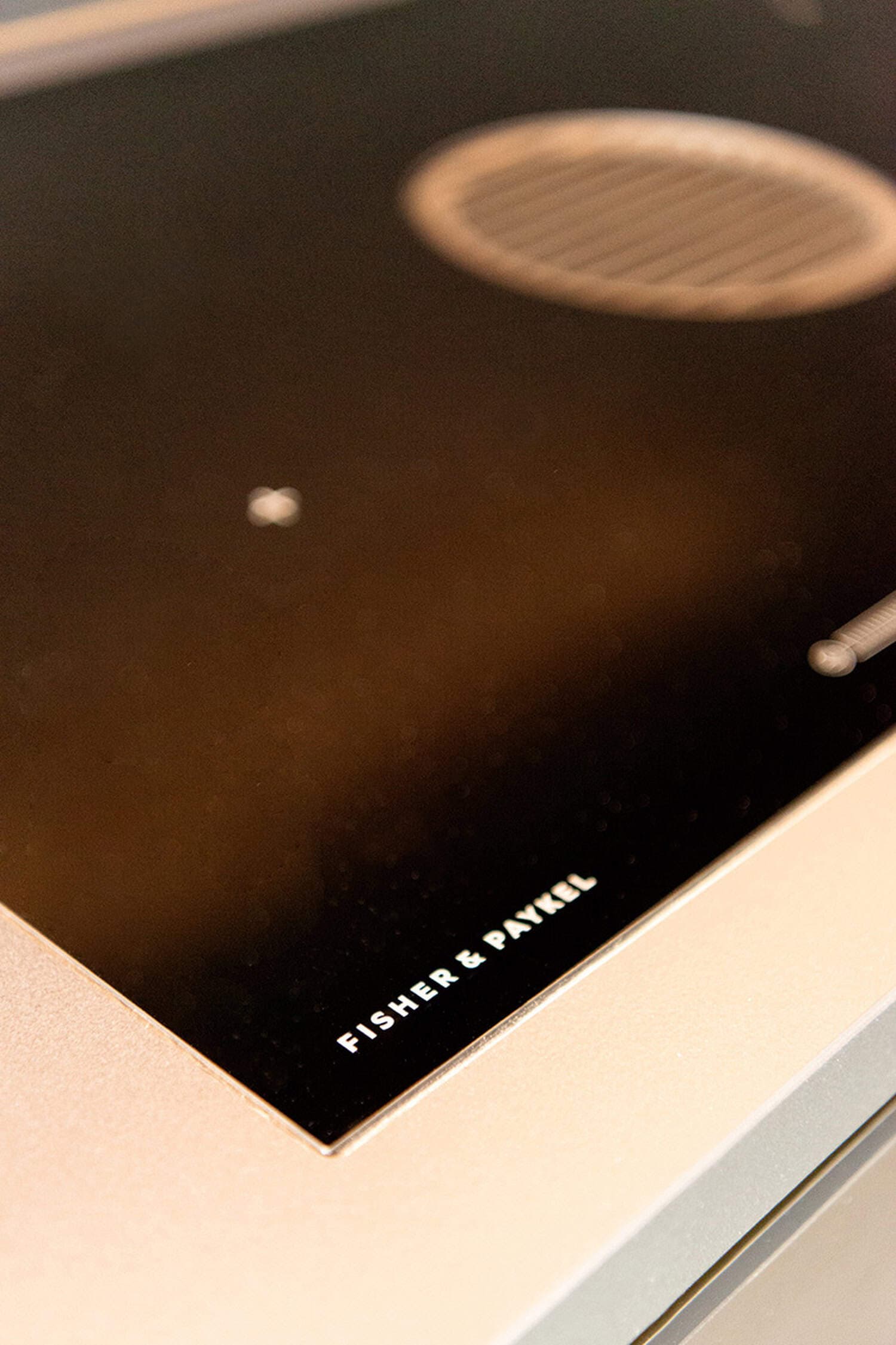 Fisher & Paykel black induction cooktop with an integrated ventilation grille.