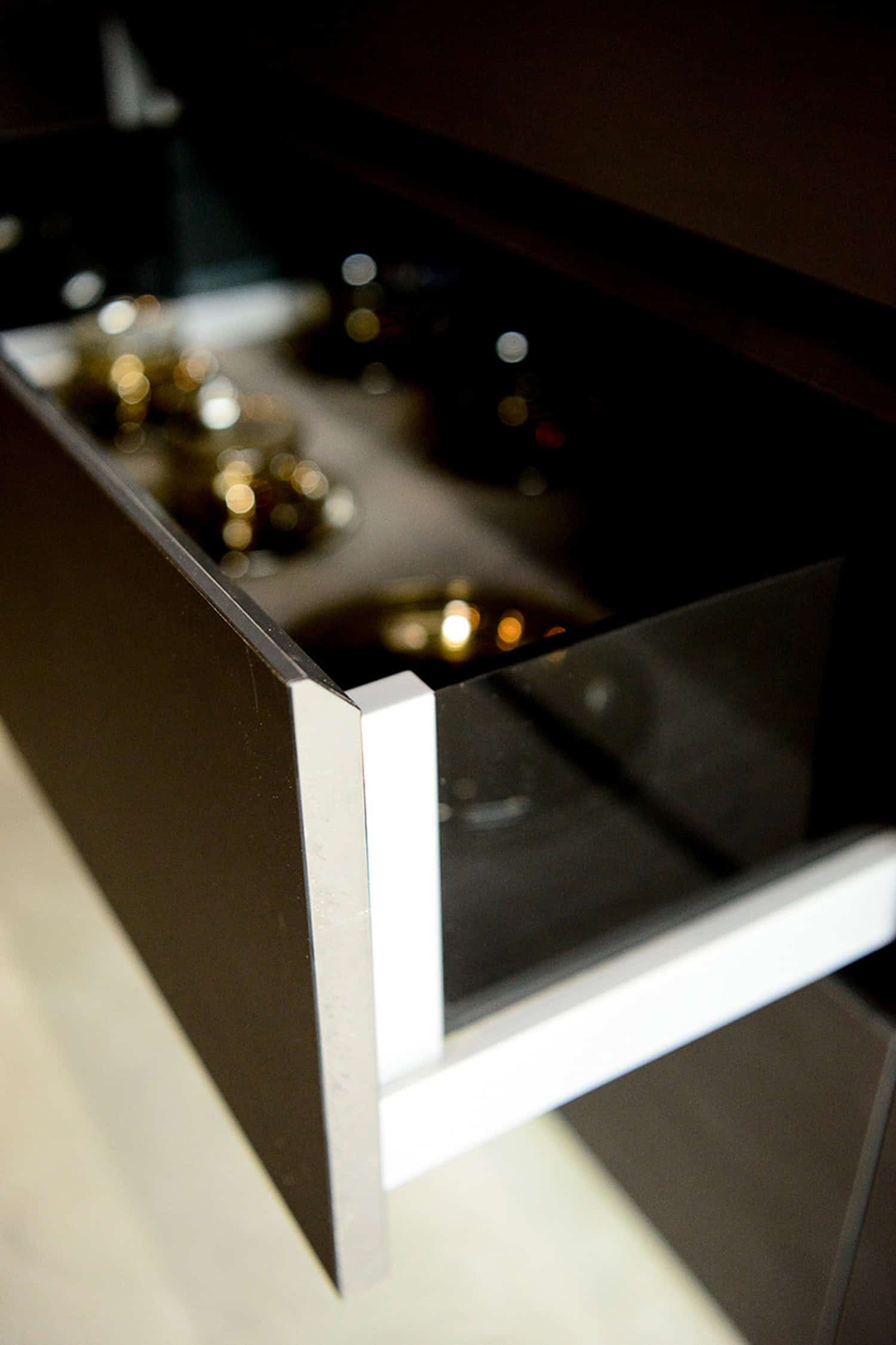 Close-up of a modern dark kitchen drawer edge showing glass side profile panels.