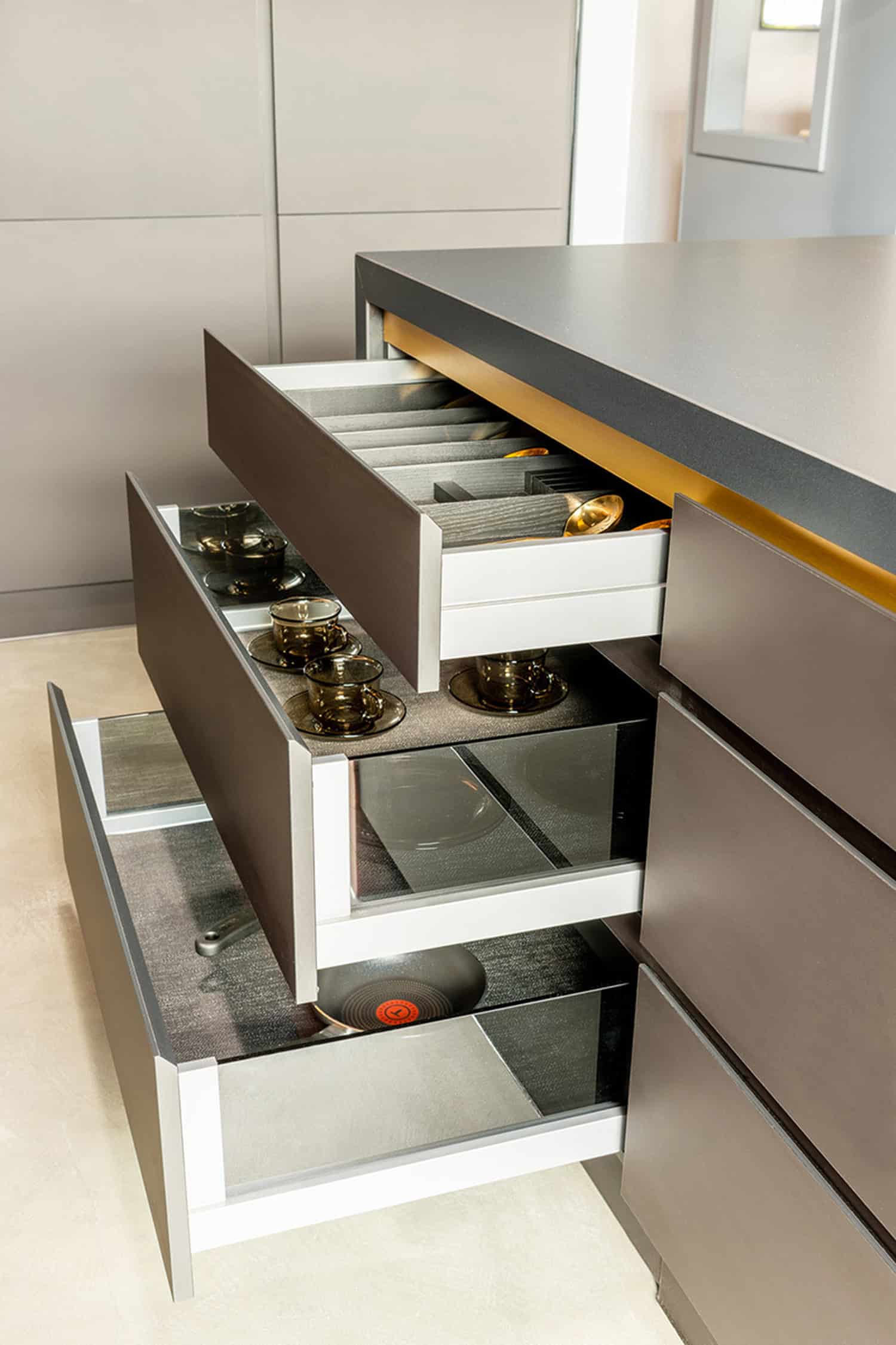 Open island drawers with custom organizers storing cutlery, tea cups, and cookware.