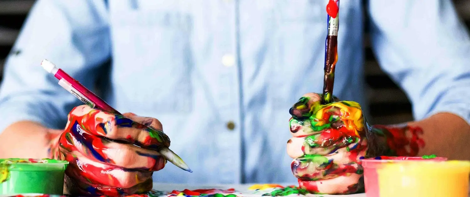 Handen vol verf en penseel, symbool voor creatief schrijven van website teksten door Totaal Webdesign Bureau intrige.