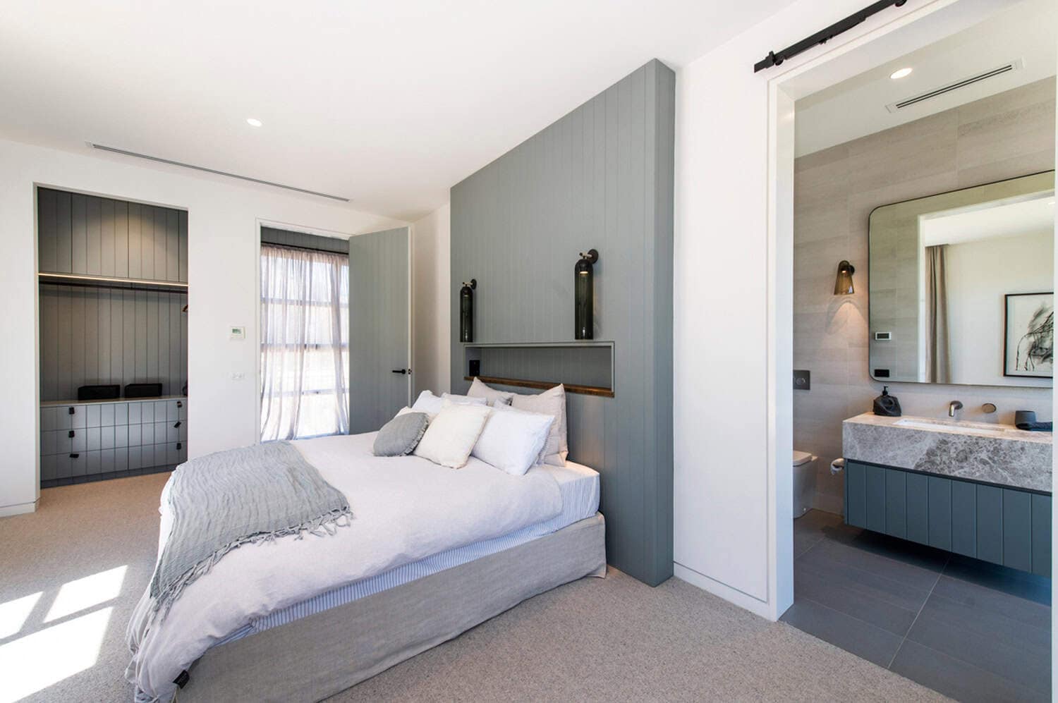 Bedroom suite featuring a sage green feature wall, walk-in robe, and adjoining marble ensuite.