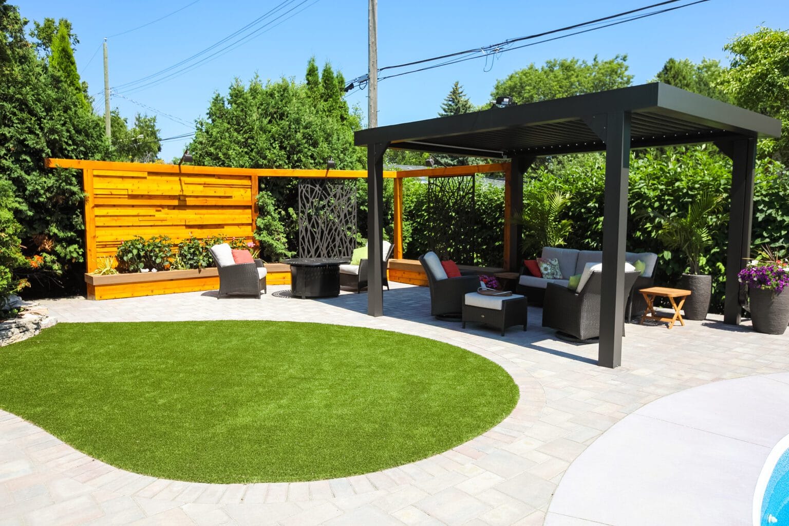 Backyard with pergola, patio seating, and artificial grass.