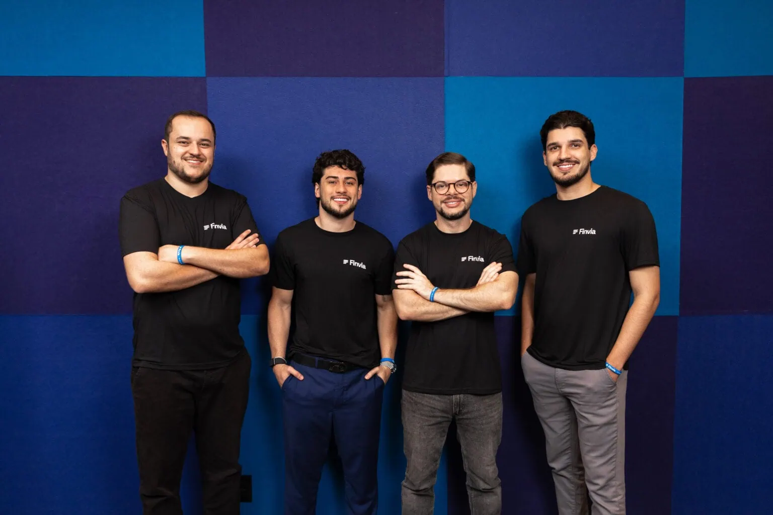 Diretoria da Finvia em frente à parede azul com as cores da marca, no escritório da empresa