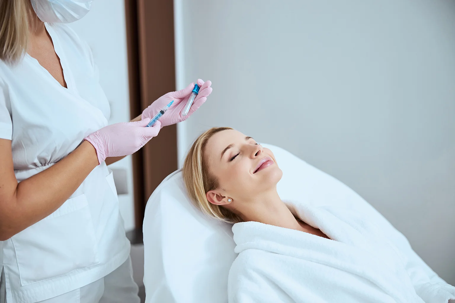 Patient smiling while doctor prepares PRP injection for facial treatment