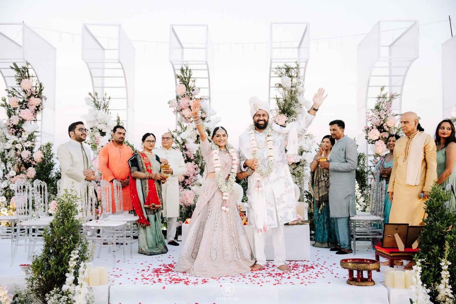 Bride and groom in flower garlands celebrate with their families under a pink floral mandap at an Indian wedding at Sheraton Hua Hin Resort & Spa