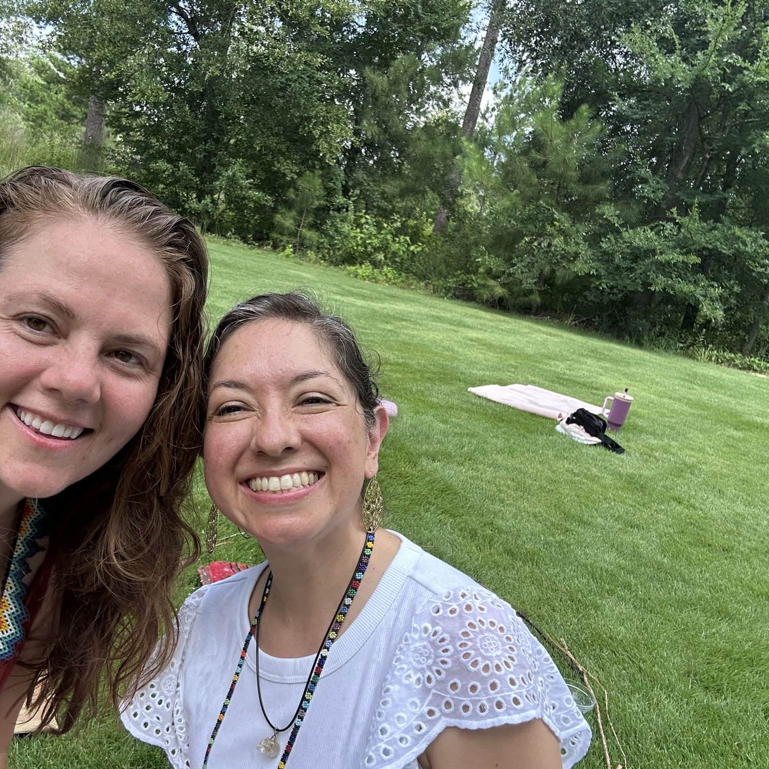 Joyful women smiling outdoors in lush green garden, thriving natural environment at Soulstice Living, celebrating wellness and community.