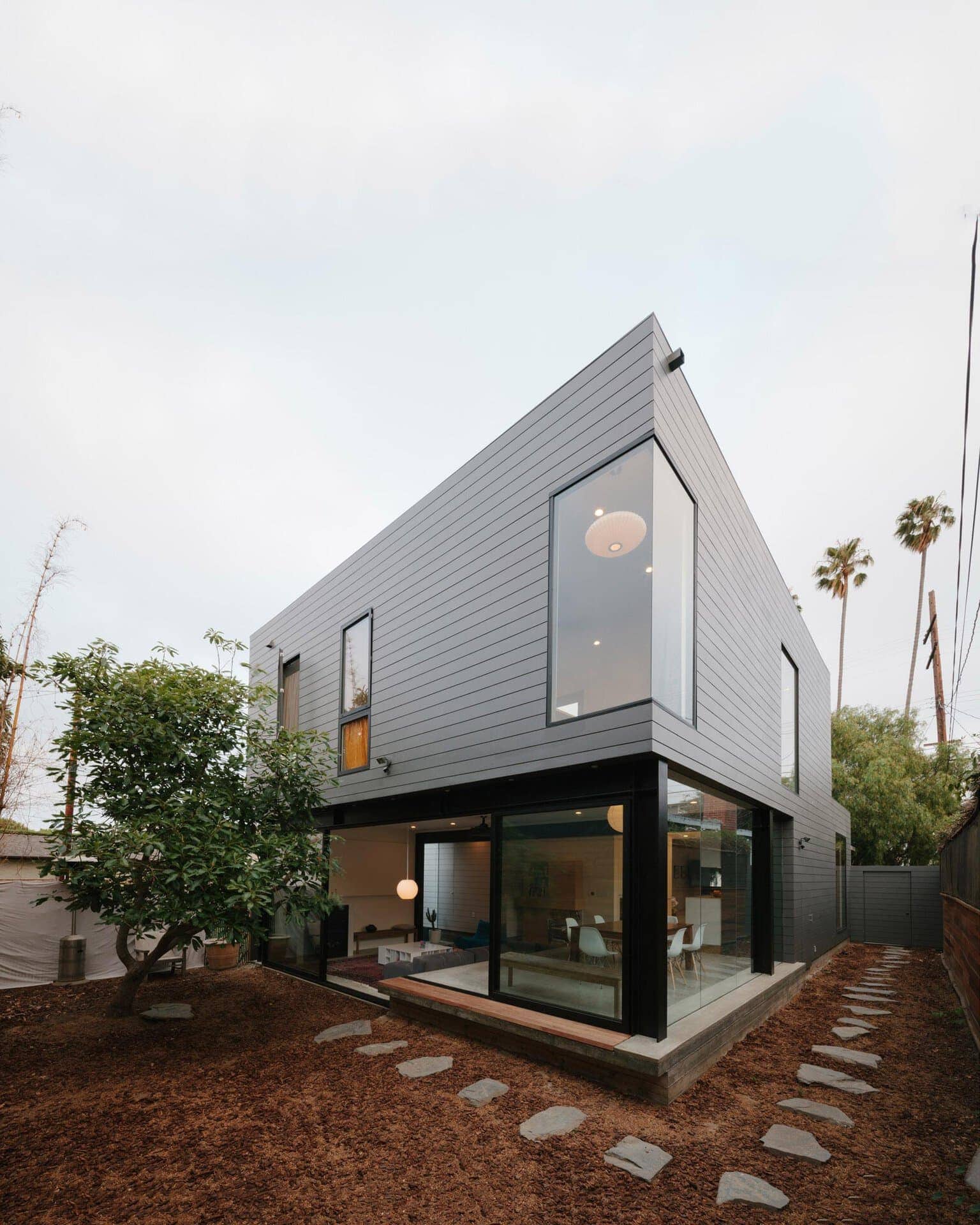 Contemporary residential home with sleek gray cladding and large glass windows.
