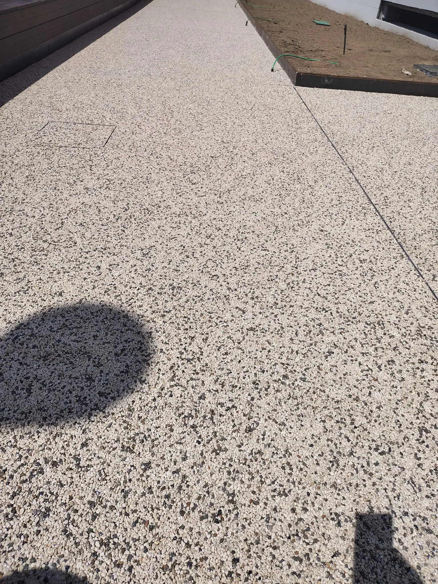 Pavimentazione drenante Prima Drain Stone® posata nell'area esterna dello student housing di Bovisa, Milano. Superficie in aggregato di pietra legato con resina poliuretanica trasparente, effetto ghiaia stabilizzata, integrata nel contesto urbano residenziale del campus universitario.