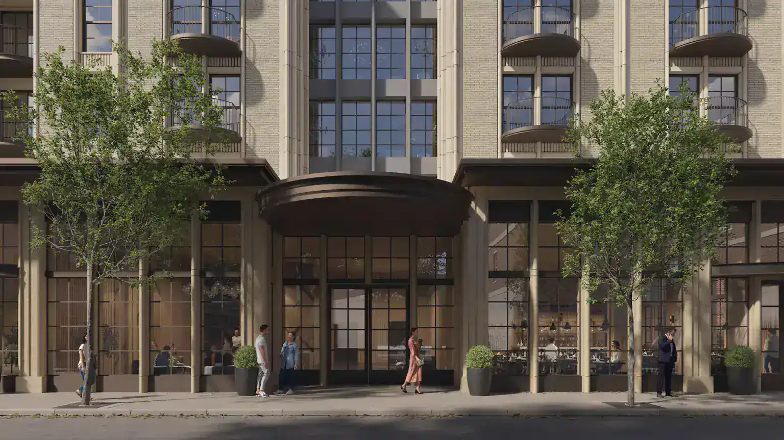 Modern mixed-use building with large glass storefronts and residential balconies, featuring beige brick facade and black window frames.