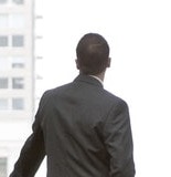 A businessman in silhouette standing at a large window in a convention center lobby.