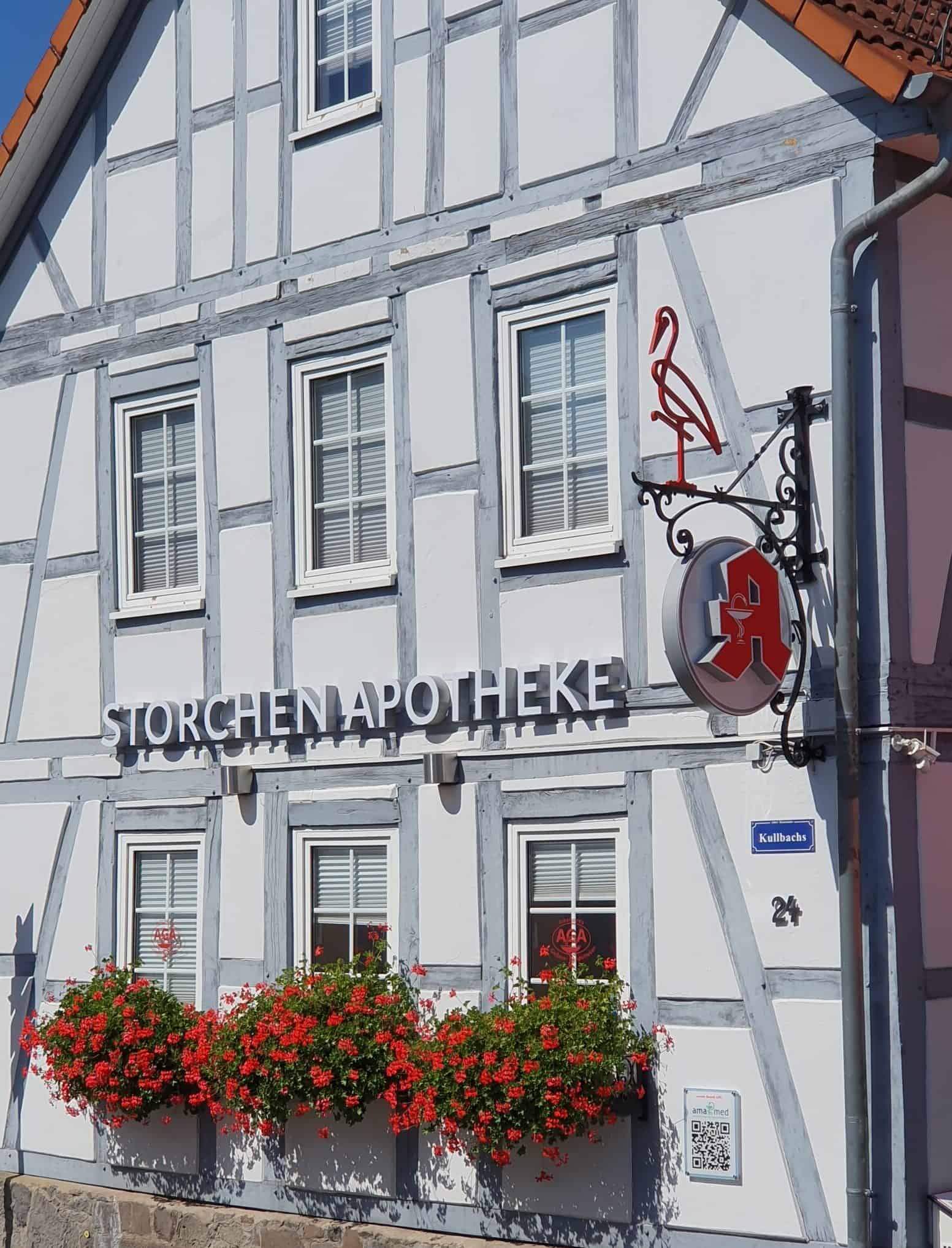 Apotheken-Schriftzug der Storchen Apotheke in Gießen. Mit historischem schmiedeeisernen Ausleger, überarbeitet mit neuem beleuchteten Apotheken-A und Storch als individuellem Erkennungsmerkmal.