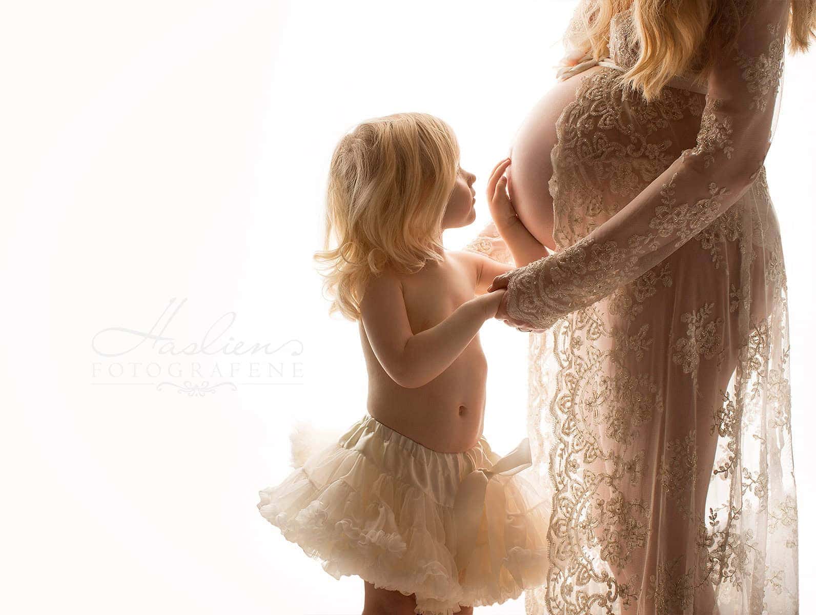 Elegant gravidfoto av en gravid kvinne og et lite barn, med fokus på kjærlighet og familiebånd, tatt i soft belysning for naturlig utseende – perfekt for gravidfotografering.