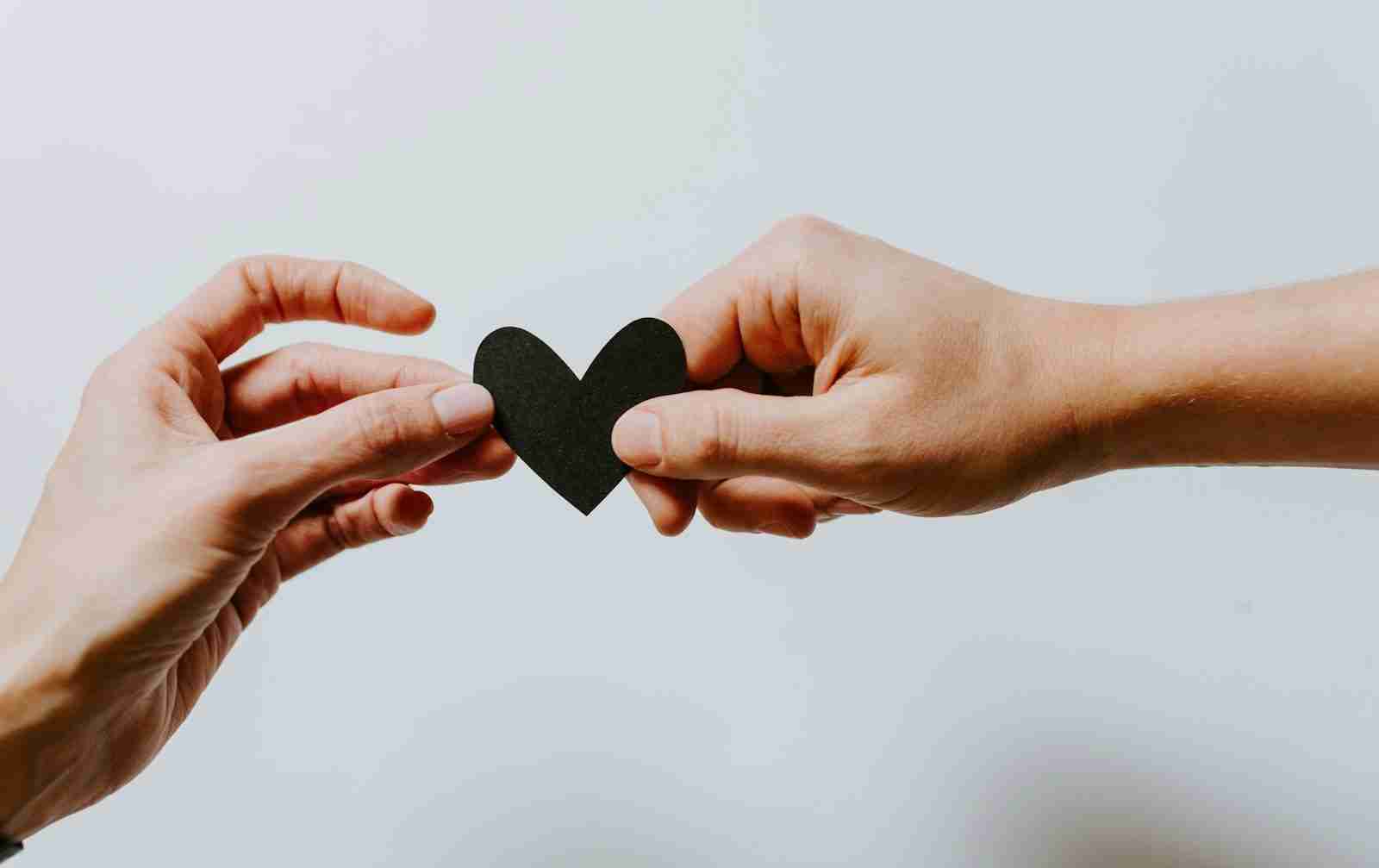 Two people holding a red heart together, a symbol of trauma therapy Farmington Hills clients can trust