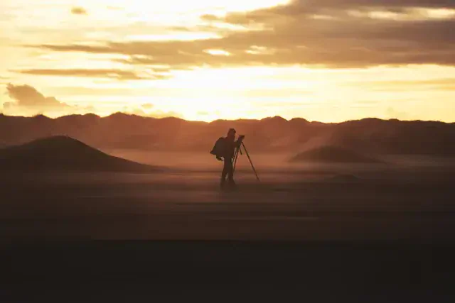 Un fotógrafo con el trípode sobre las dunas, al amanecer. Foto de Antun