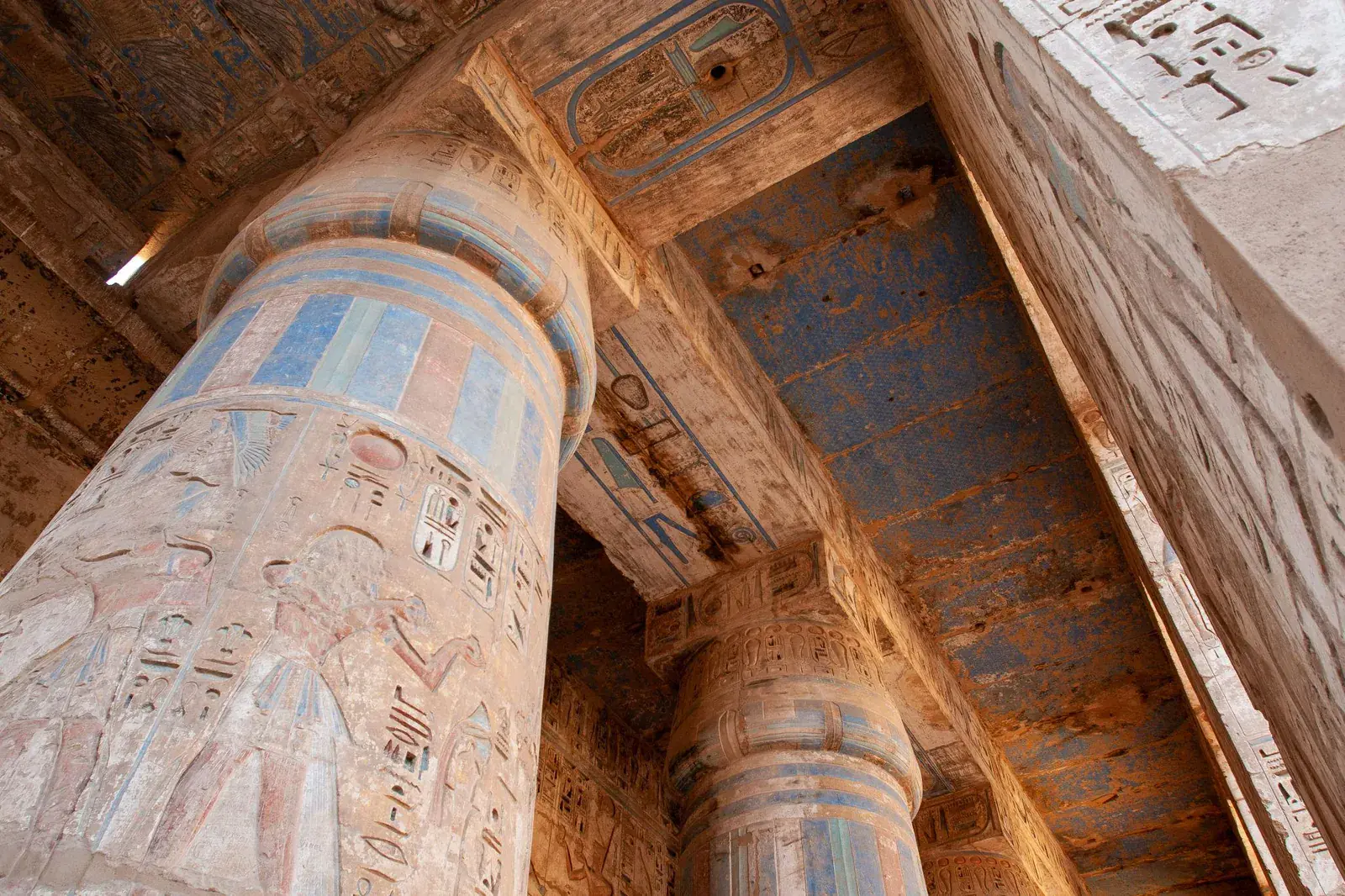 Blue painted ceiling and decorated columns inside the temple of Ramesses III