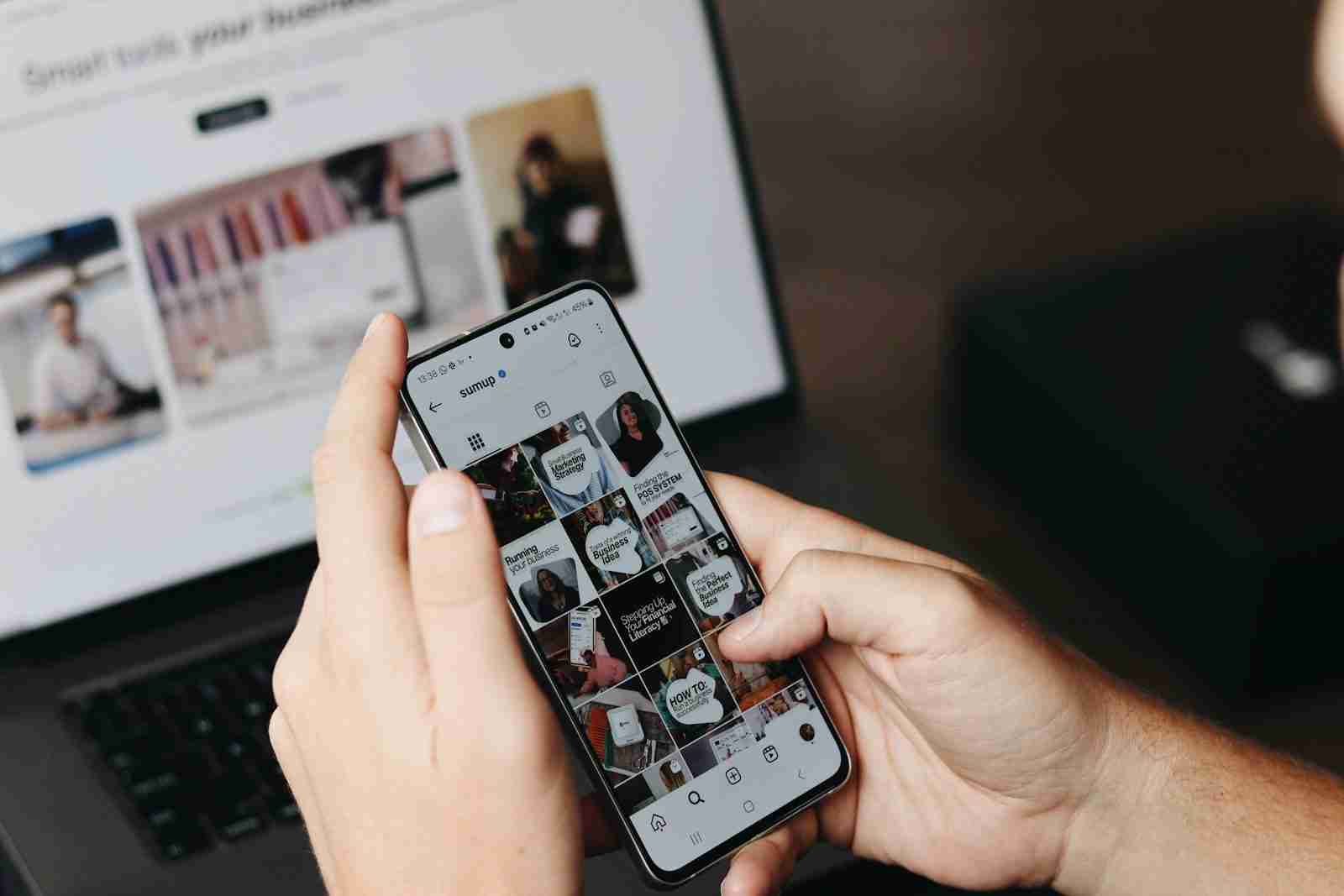 A person holding a cell phone in front of a laptop, representing the restless habit a somatic therapist in Detroit, MI sees often.