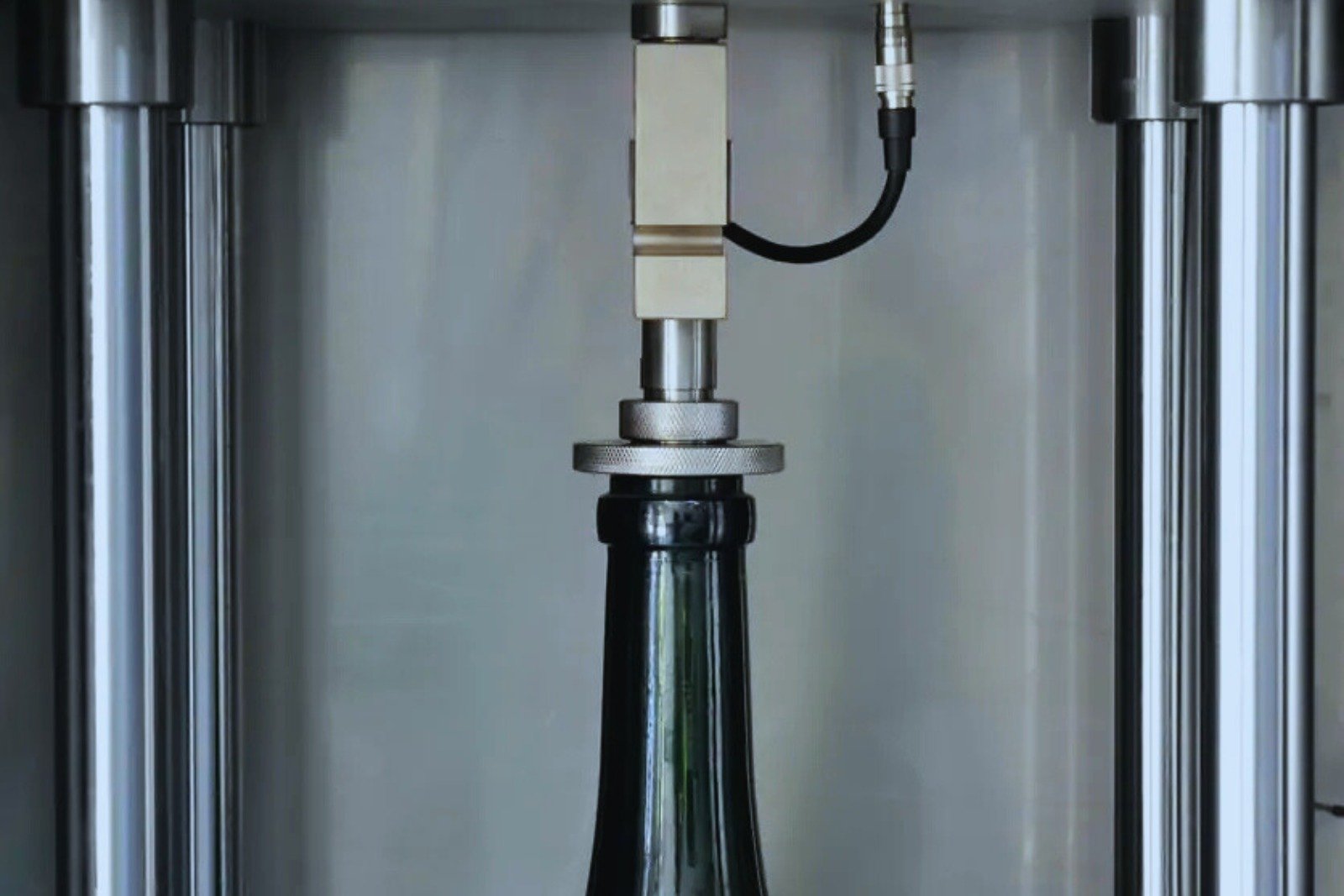 Bottle top load tester measuring strength of a plastic bottle