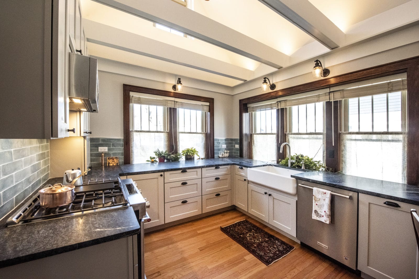 Cozy kitchen with grey cabinets & drawers, black granite countertops, silver appliances, 5 windows
