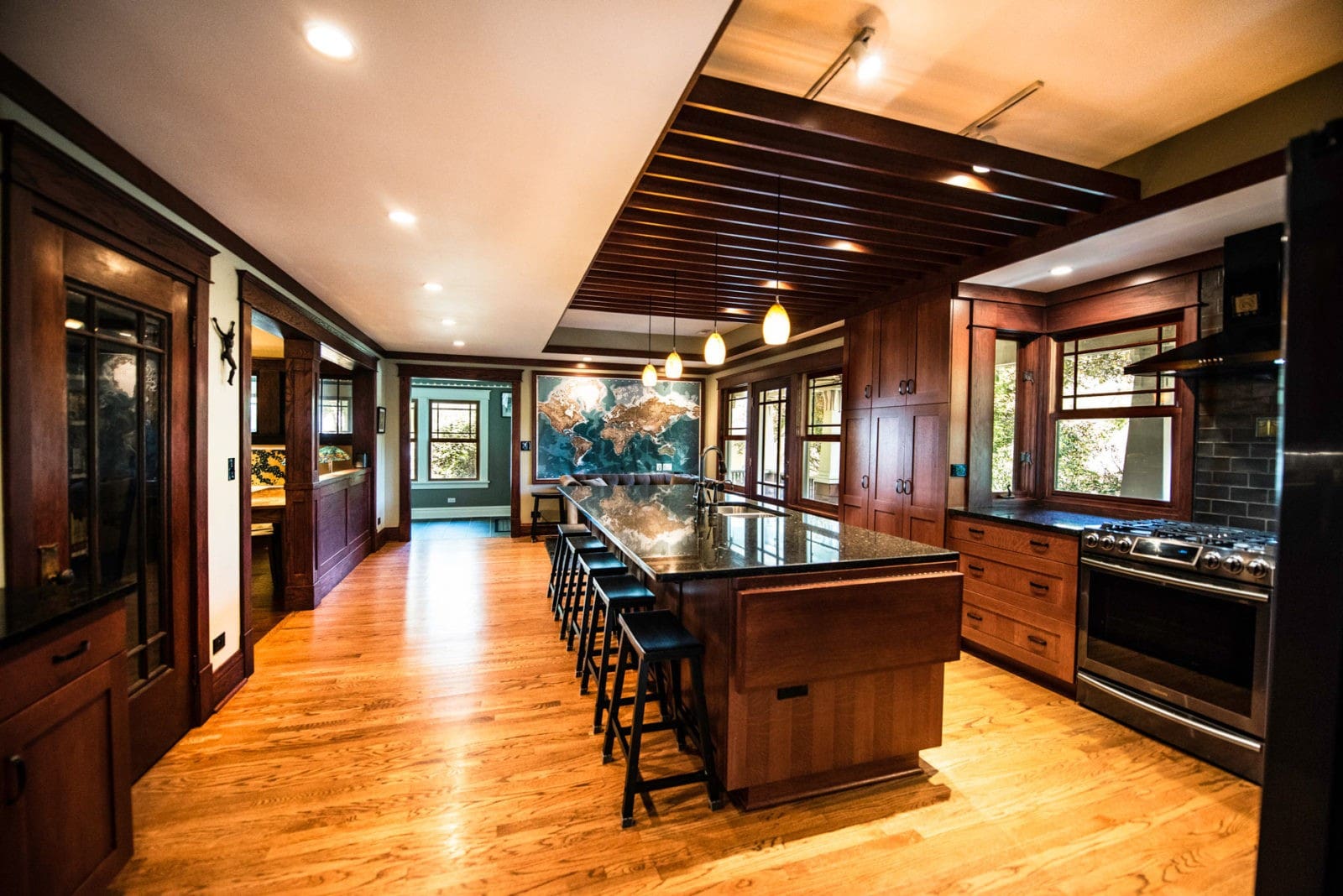 Large kitchen with large island, bar chairs, cabinets, appliances, & couch at far end of room