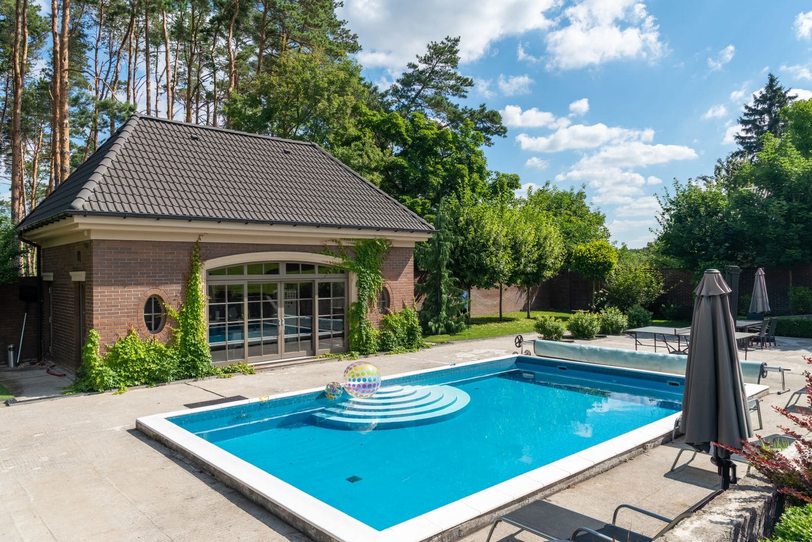 Saltwater pool in a landscaped residential backyard with patio and pool house