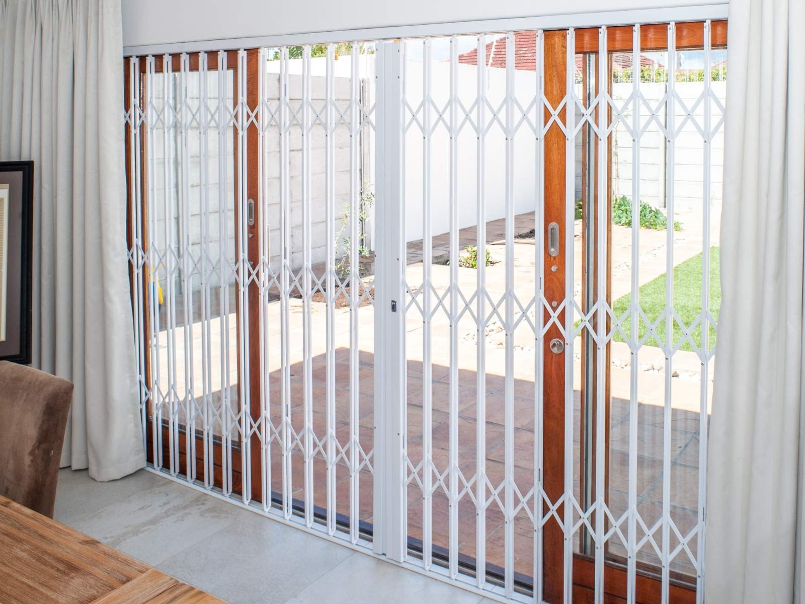 White trellis door installed over a large glass sliding door for indoor security and natural light access.