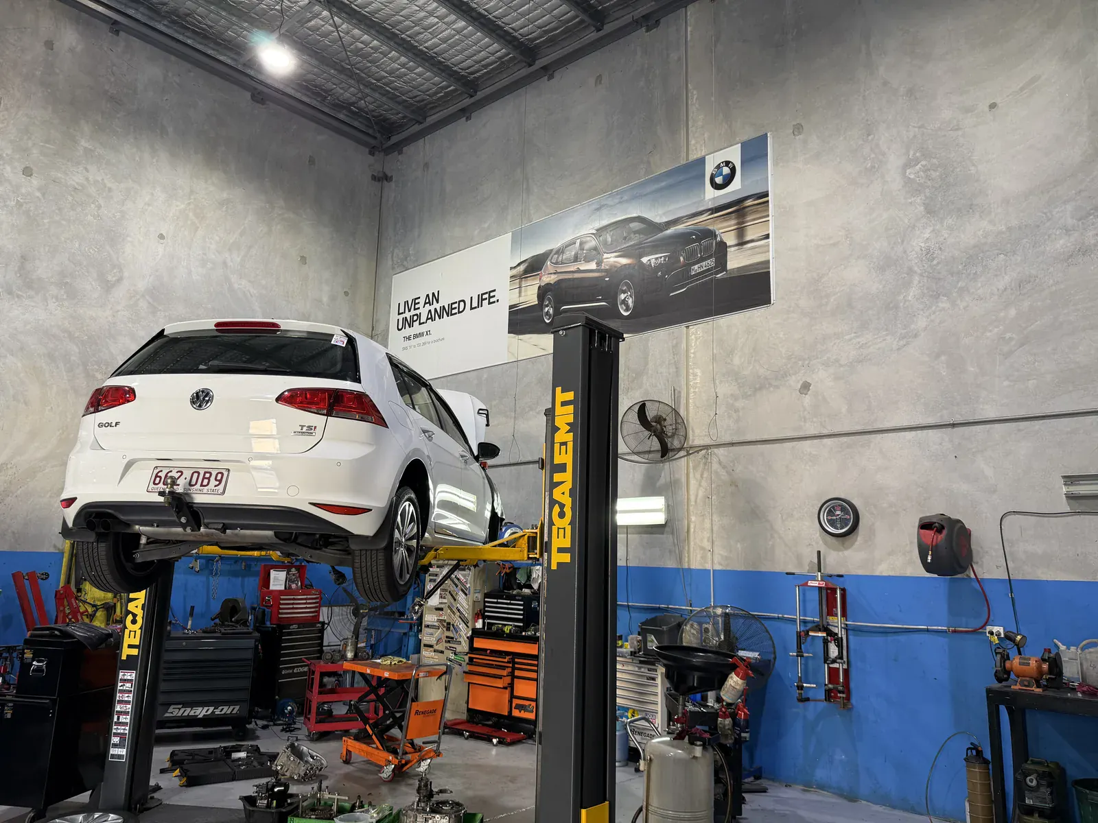 Volkswagen Golf raised on a two-post hoist for inspection inside the Euro-Aus Performance workshop in Capalaba