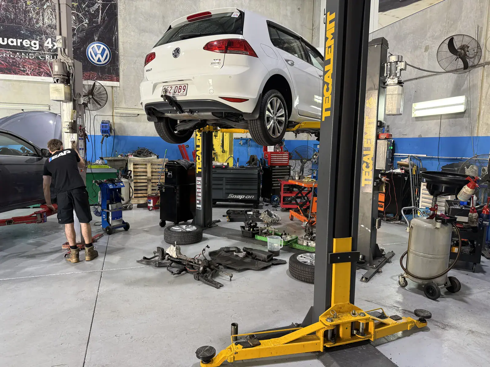 Euro-Aus Performance technician working beneath a Volkswagen Golf on the hoist at the Capalaba workshop