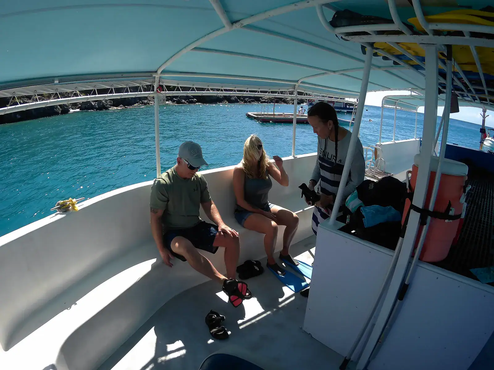 SNUBA guide preparing equipment with first-time guests aboard the boat in clear Little Bay water