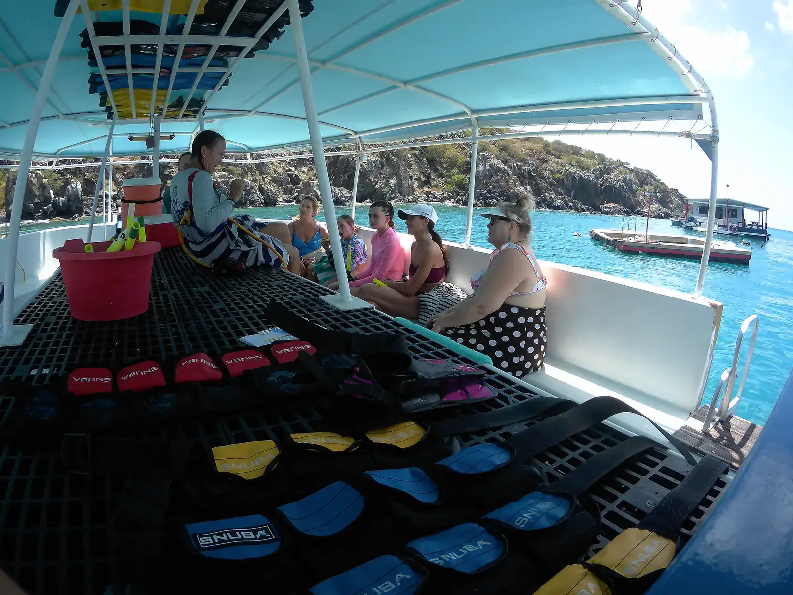 SNUBA guide briefing guests beside organized harnesses aboard the boat in clear Little Bay water