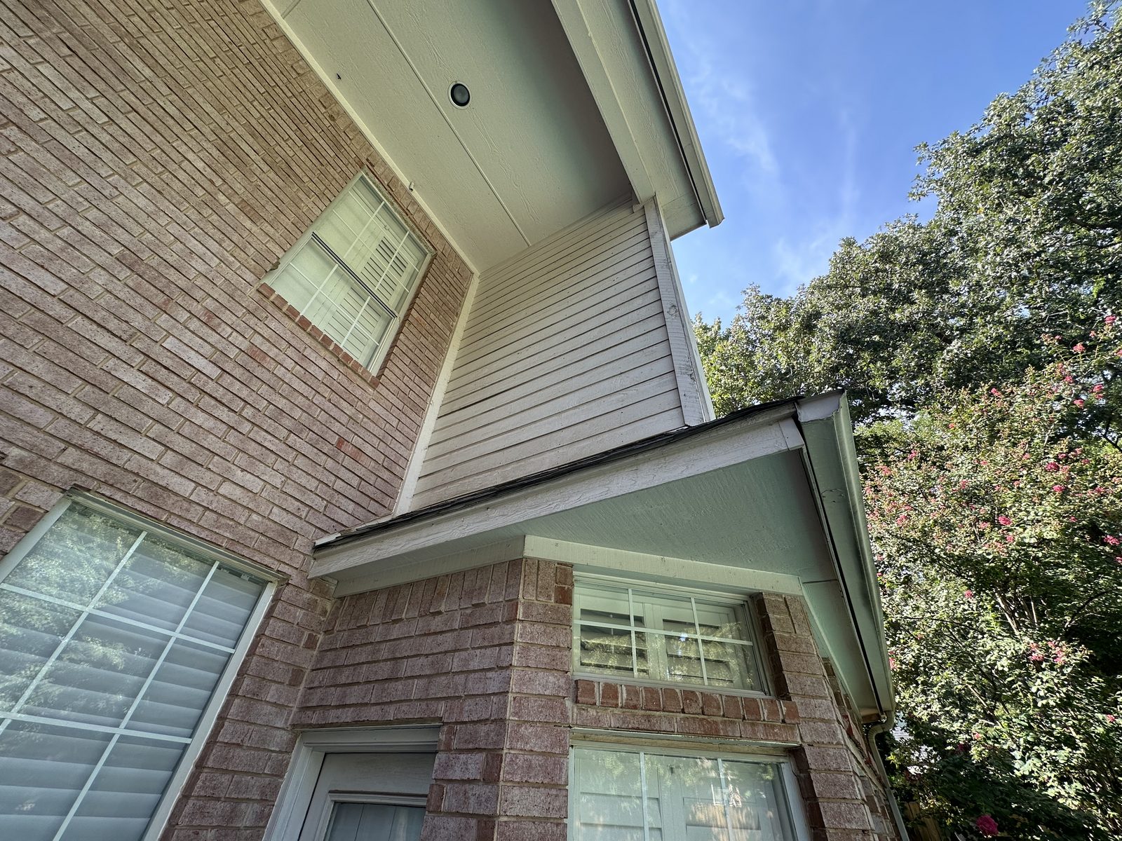 Residential roofing installation with visible overhang and brick exterior