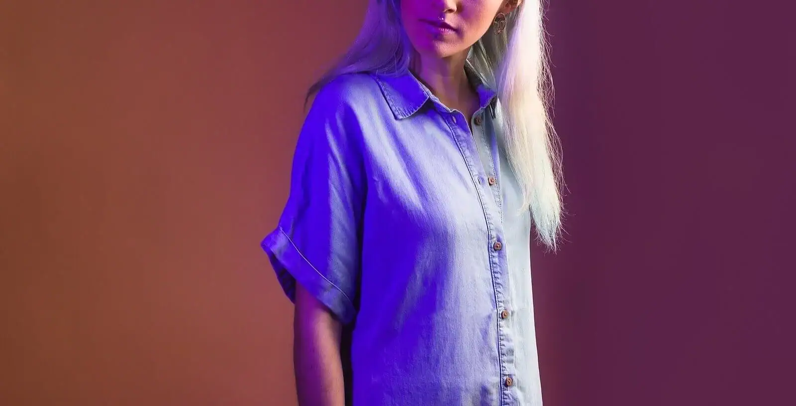 Person wearing a light denim shirt, partially visible face, illuminated by purple and orange studio lighting. Looking for a way to navigate the unique challenges of empaths? Our caring empath counselings in Detroit can help you better understand yourself. Contact us today!