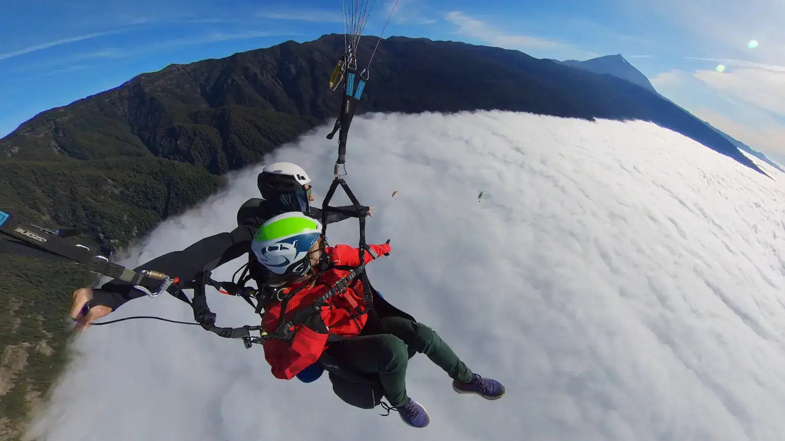 Vuelo biplaza en parapente sobre el mar de nubes, con la ladera del Teide al fondo y cielo despejado