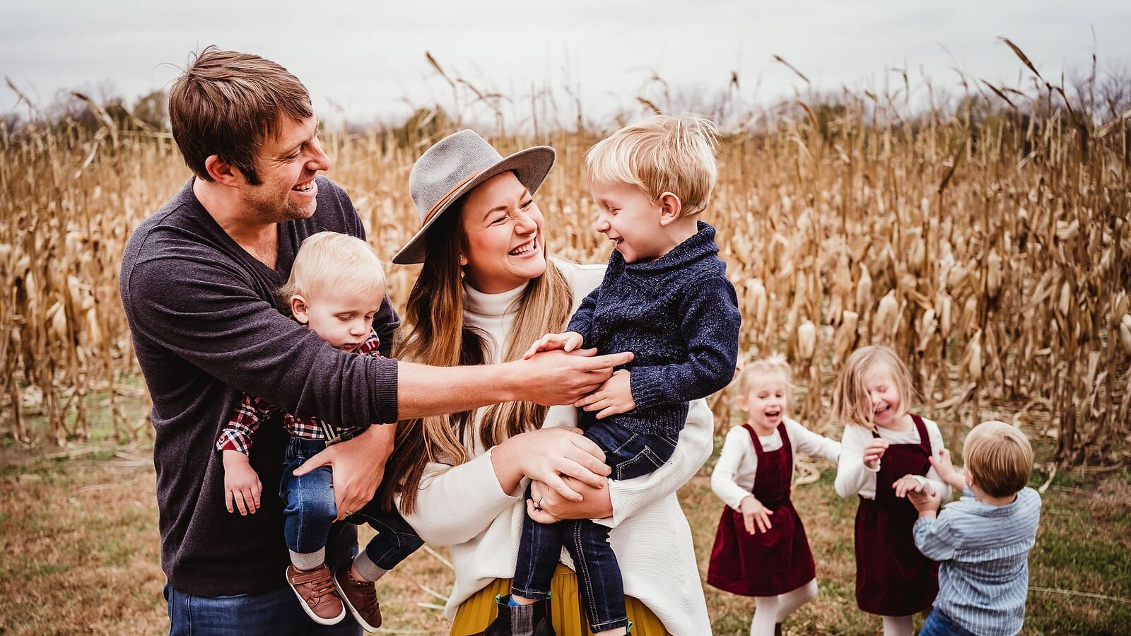 Family portrait photo of kids playing running and couple hugging