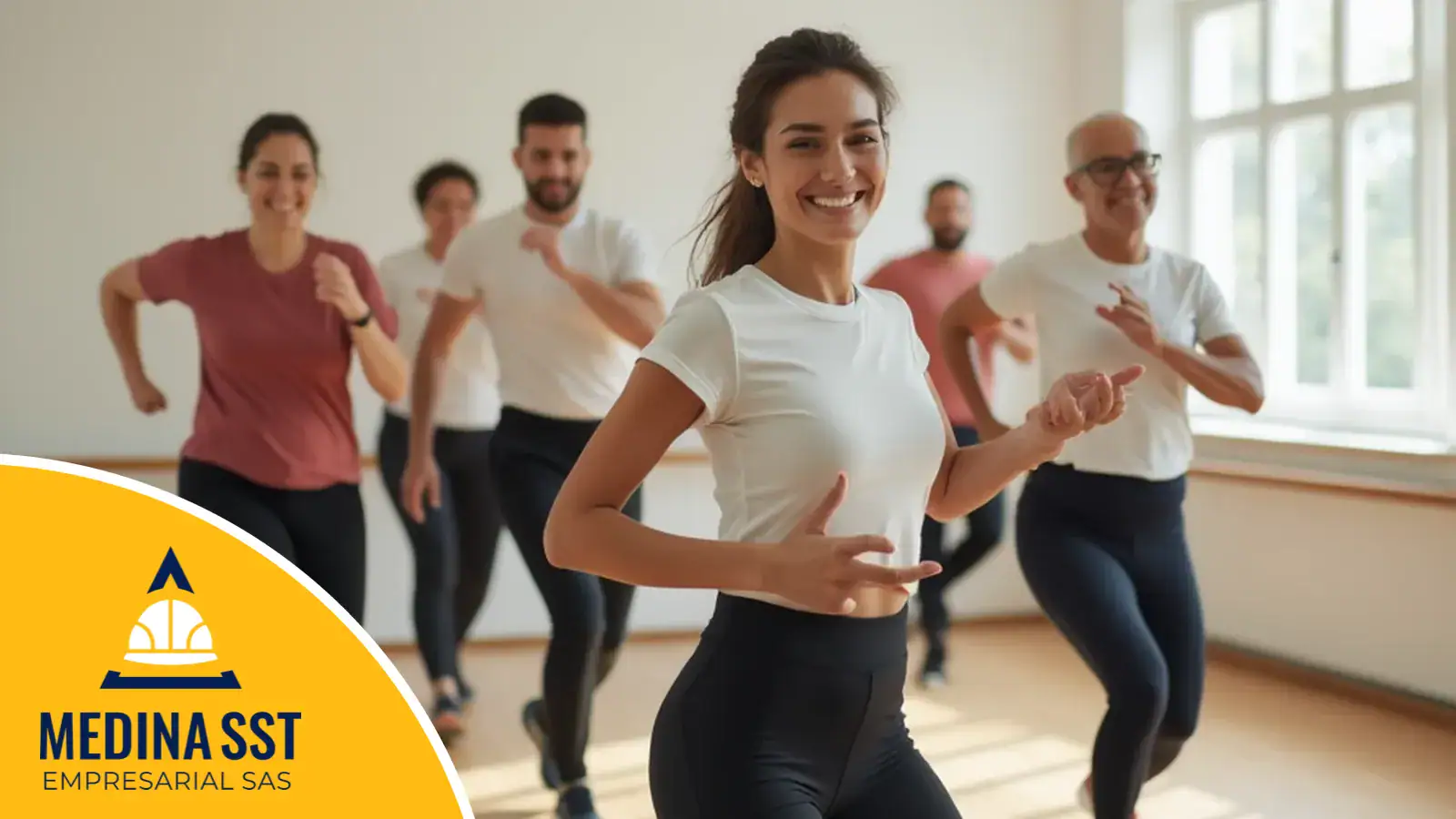 Instructora de rumbaterapia sonriendo en el salón de una empresa, con trabajadores bailando detrás durante la semana de la salud